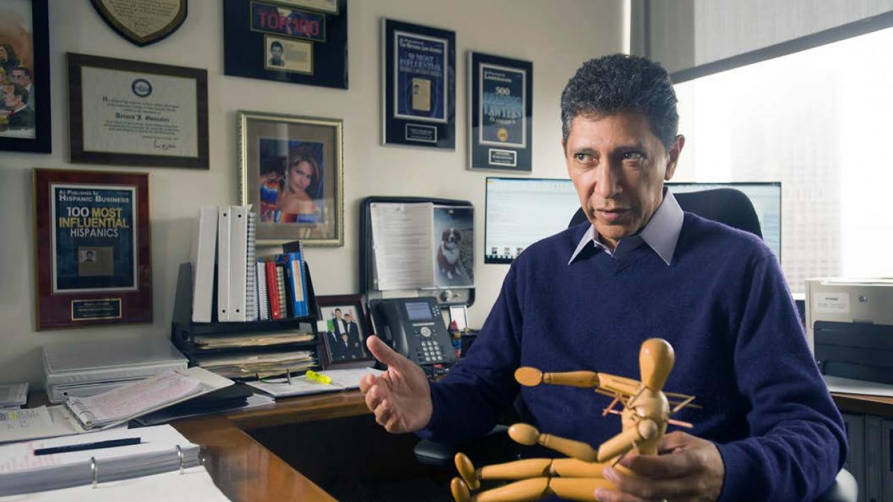 González demonstrates how he used a mannequin as an exhibit in his $12.5 million police excessive force case, earning the family of the victim the largest amount ever awarded for a police shooting in California. Arturo Gonzalez sitting at a desk