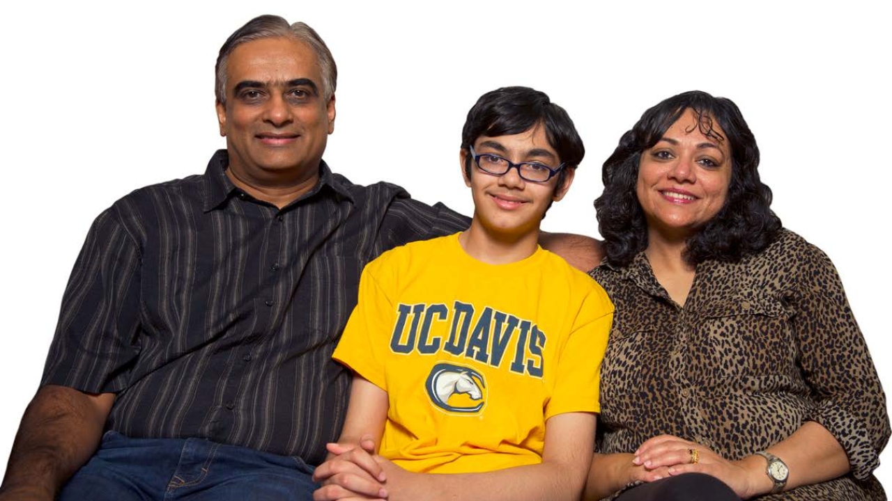 Bijou and Taji Abraham sit beside their gifted son, Tanishq, who— at 13 years old—eagerly begins his junior year at UC Davis this fall. Family sitting together