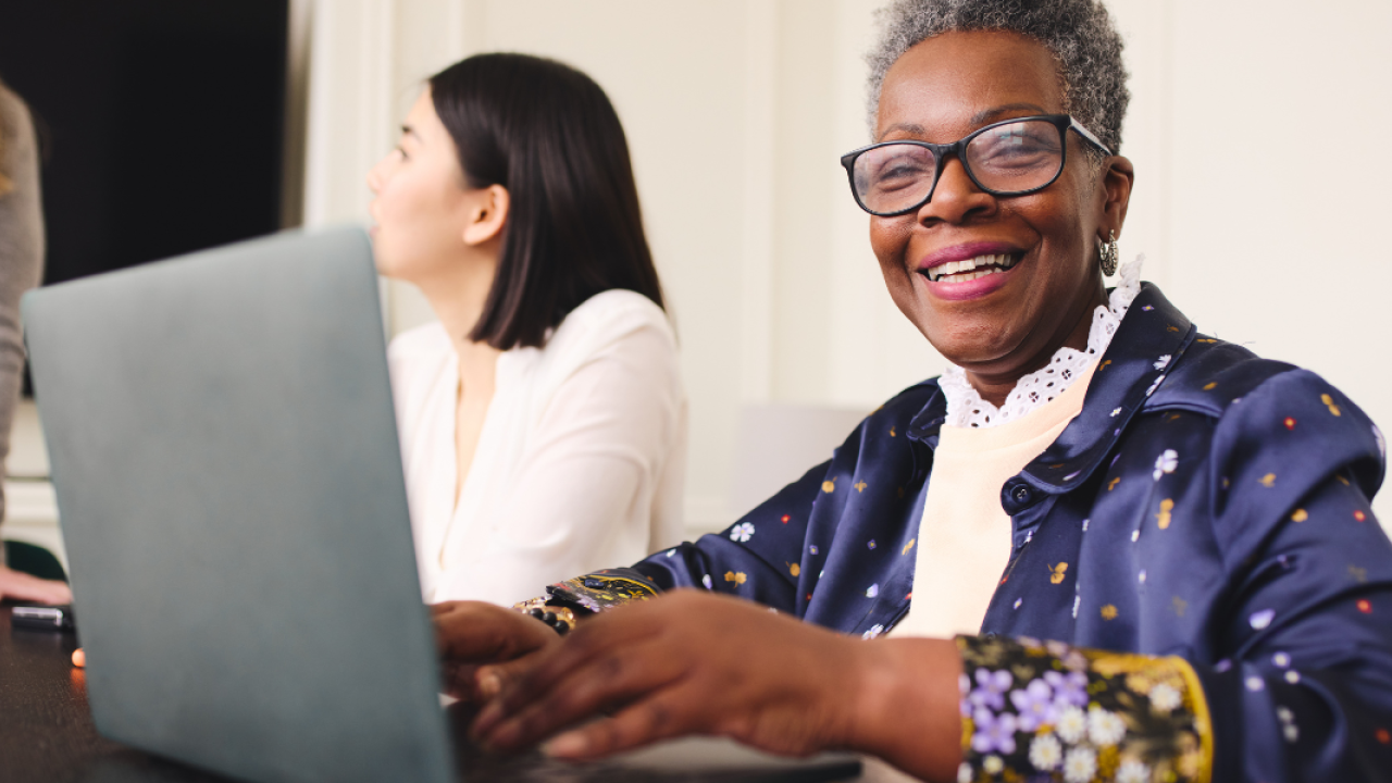 Older woman smiling and typing on her laptop