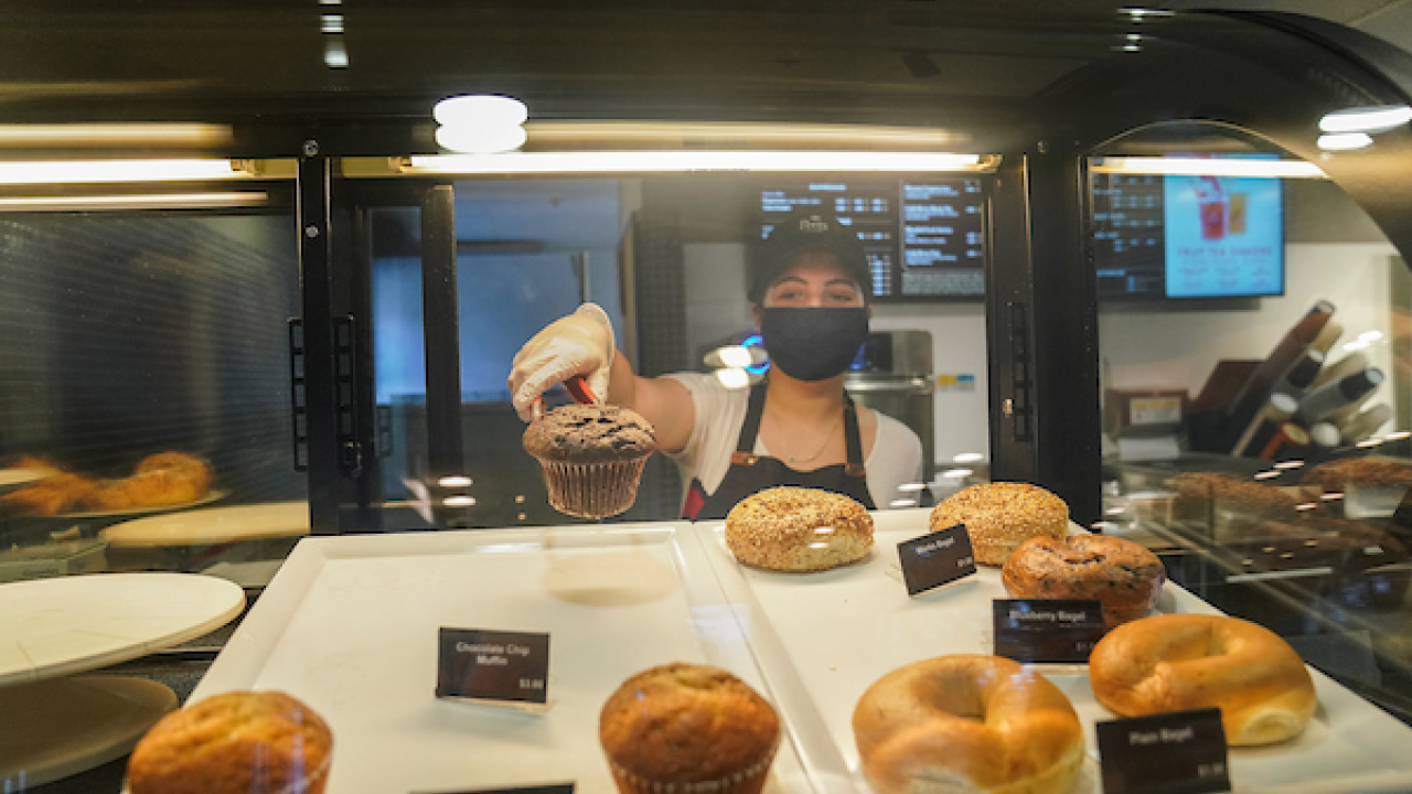 Coffee House employee grabbing a muffin with tongs 
