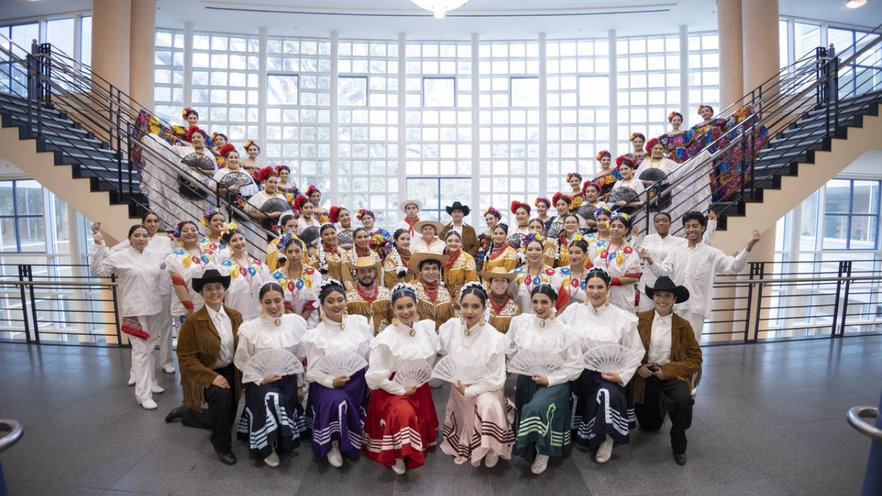 Members of Danzantes Del Alma's 45th Annual Show stand together between two staircases