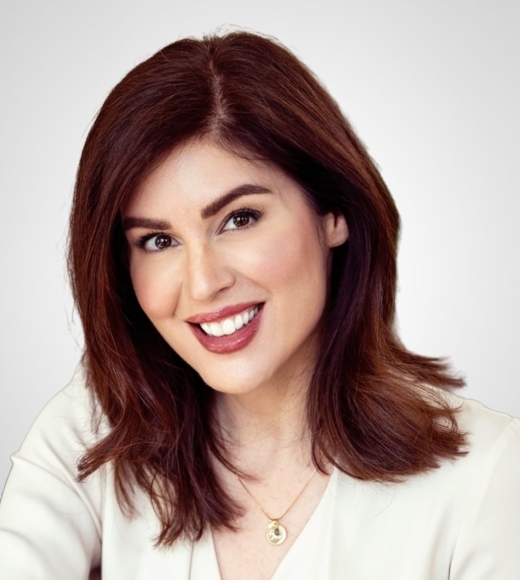 Headshot photograph of a smiling woman with shoulder-length brown hair and white blouse