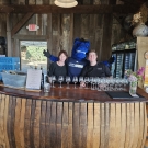 Gunrock poses with two bartenders behind the bar of a rustic winery.