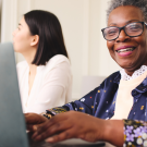 Older woman smiling and typing on her laptop