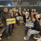 Fresno alumni holding signs saying "Go Ags!" and "Proud UC Davis Alumni" as well as gingerbread houses