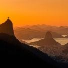 Sunset view over mountains and city, with Christ the Redeemer statue silhouetted.