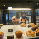 Coffee House employee grabbing a muffin with tongs 