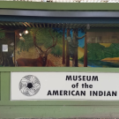 Green building exterior featuring a sign that reads "Museum of the American Indian."